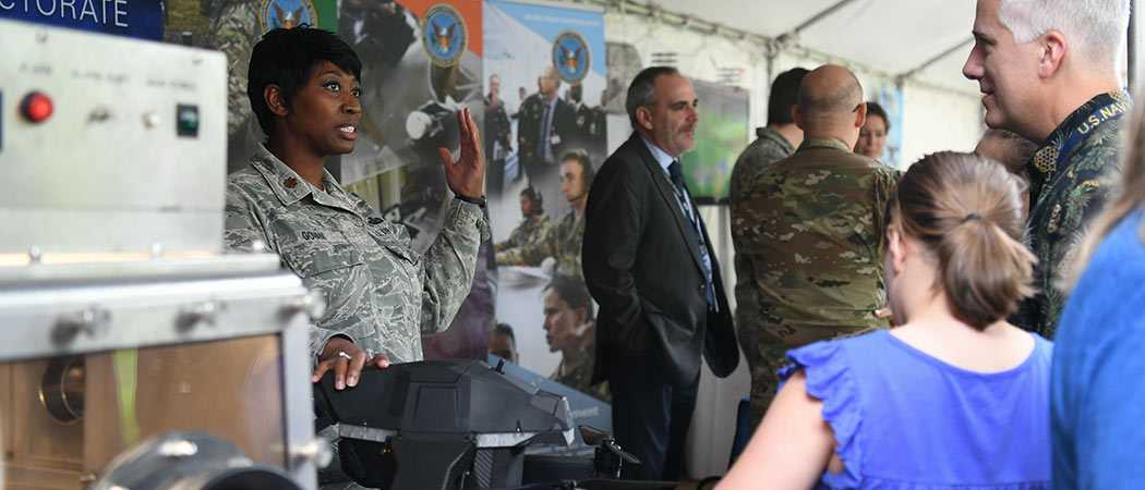 A military member in a booth demonstrating a piece of equipment for attendees of the Lab Day.